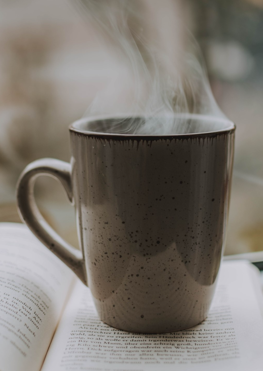 Photo of a steaming mug, resting on an open book.