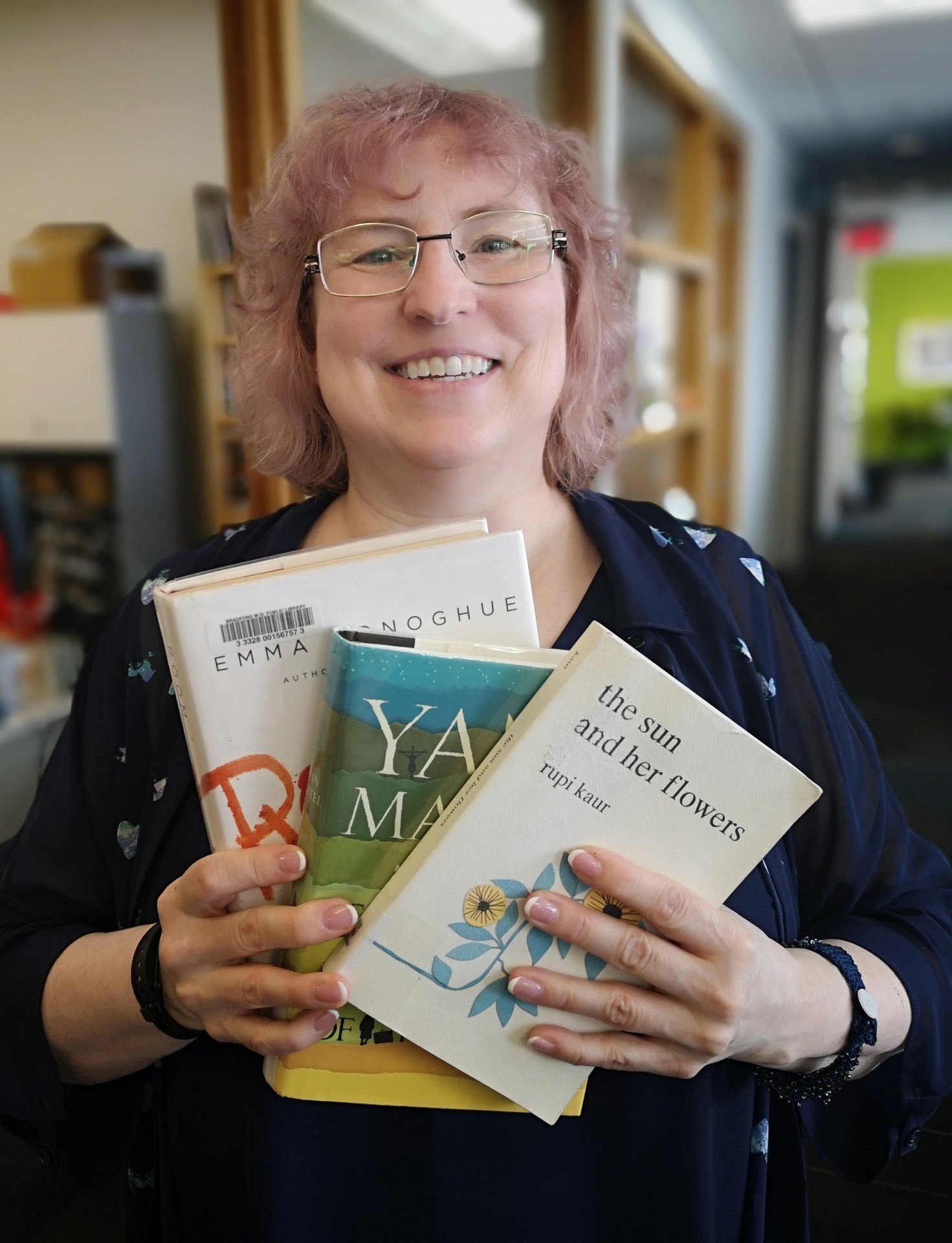 Photo of Nina Cunniff holding up 3 books and smiling