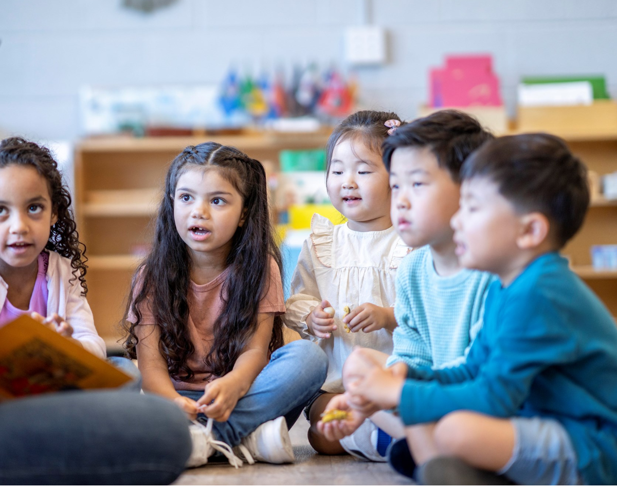 A group of children sit on the floor listening to a story